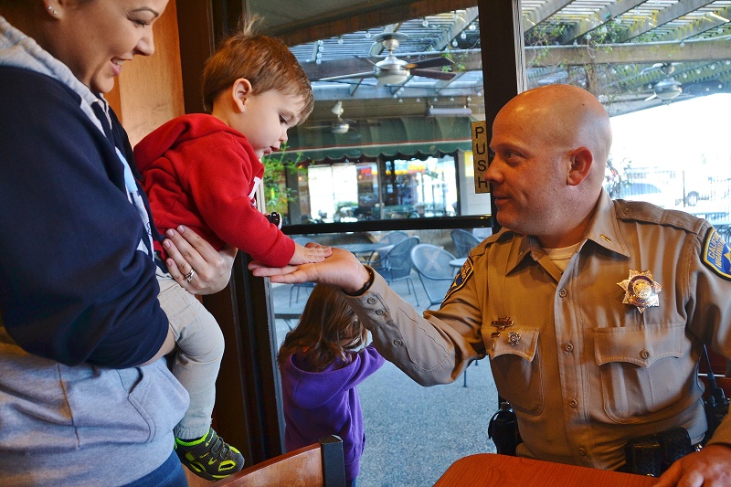 Mom Bevin Sternburg holds 18 mo. old Sawyer to high-five CHP Commander Jason Daughrity - photo by Gina Clugston