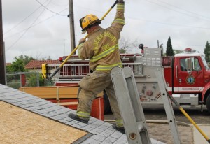Cal Fire Firefighter Nick Sciaqua (Bass Lake Station) “sounds” a roof, checking for strength and safety - photo by Bill Ritchey