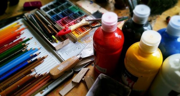 Image of an artist's table, with paint and colored pencils.