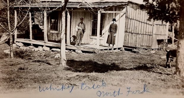 Nearly a century-old image of a couple on the front porch of a cabin.