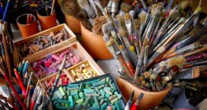 Image of paint brushes and pastel chalks.