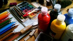 Image of brushes, art pencils, and paint. 