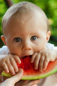 Image of a baby eating a watermelon. 