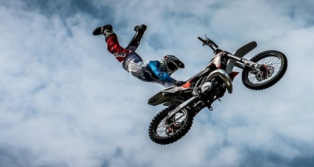Image of a man riding a motorcycle through the air.