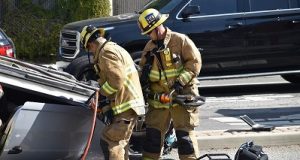 Image of firefighters using the jaws of life to rescue someone trapped in car.