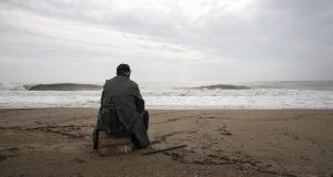 Image of a man sitting alone on a beach.