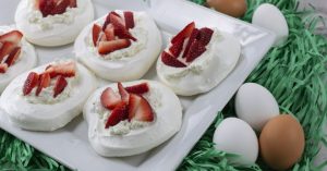 Image of meringue nests with strawberries and whipped cream.