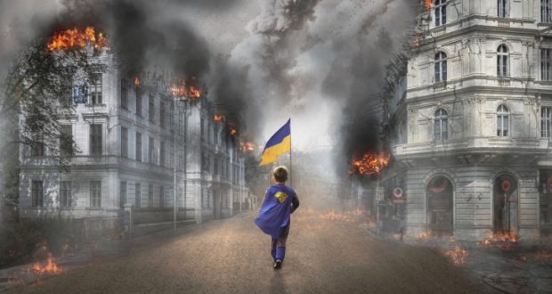 Image of a young boy carrying a Ukrainian flag through a war zone.