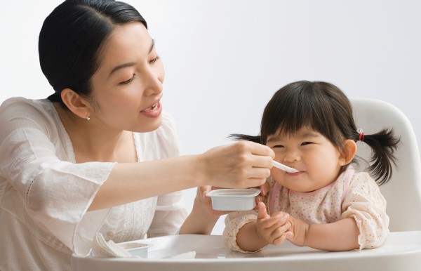 Image of a mother feeding a small child. 