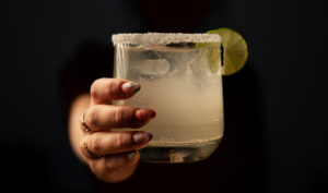 Image of a person offering a margarita.