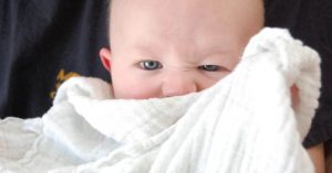 Image of a baby hiding behind a blanket.