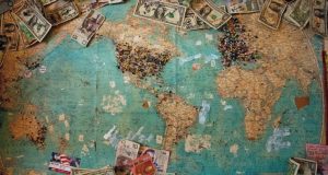 Image of an antique world map with money on it.