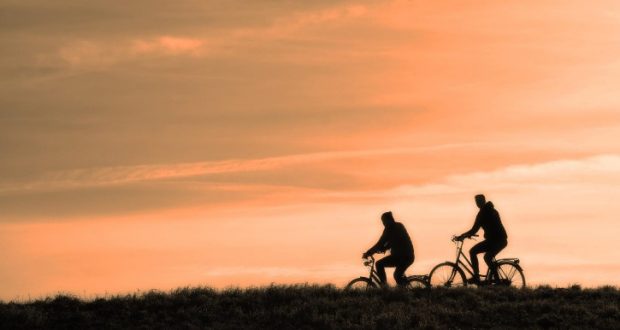 Image of two cyclists riding bikes at sunset.