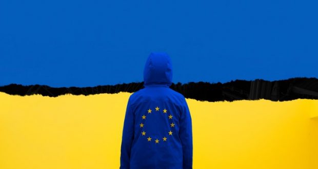 Image of the Ukraine flag with a person standing in front of it.