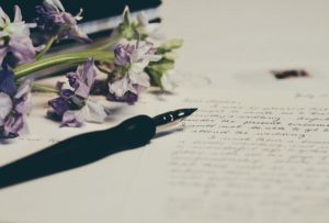 Image of a fountain pen resting on a book of poetry.