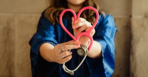 Image of a doctor holding up a stethoscope in the shape of a heart.