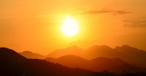 Image of the sun over mountaintops.