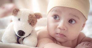 Image of a baby and a toy dog plushie.
