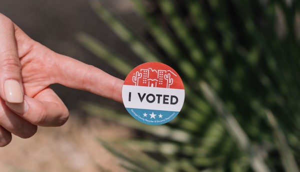 Image of a hand holding an "I VOTED" button. 