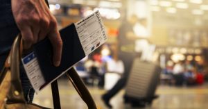 Image of a person walking through an airport with a ticket and boarding pass.
