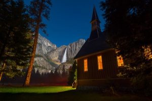 Image of a cabin with a moonbow in the background.