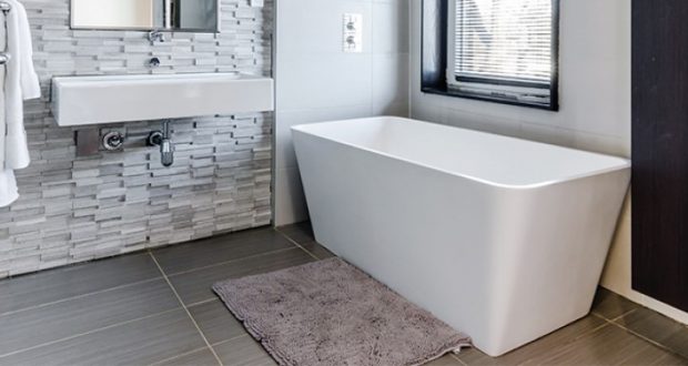 Image of a bathroom with dark tiling and a white bathtub.