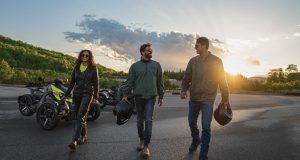 Image of three people walking away from their motorcycles after a long ride.