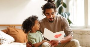 Image of a father reading a Father's Day card with his child.