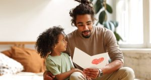 Image of a father reading a Father's Day card with his child.
