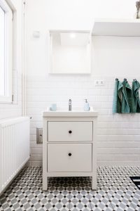 Image of a bathroom with white walls and tiles with geometric designs. 
