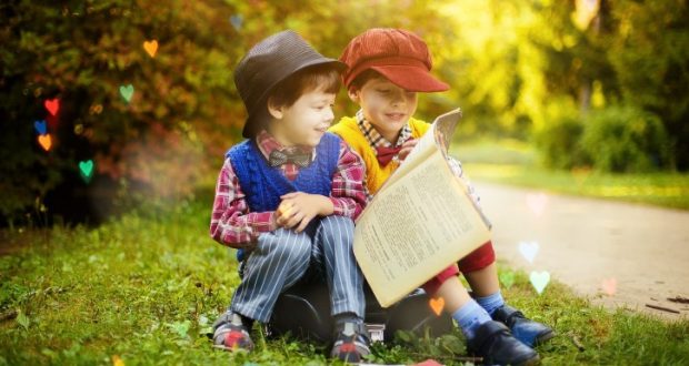 Image of two young children reading a book.