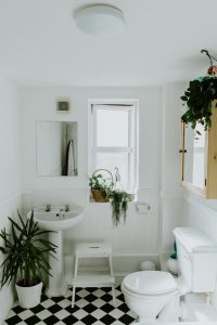 Image of a bathroom with white walls and black and white tiles. 