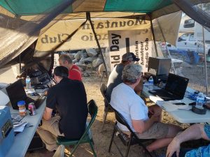 Image of Local Mountain Amateur Radio Club members at an annual Field Day event last year in Oakhurst as they huddle together while making contact on their radios with other ham club members at similar events that day around the United States.