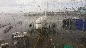 Image of planes in the rain at an airport through a window.
