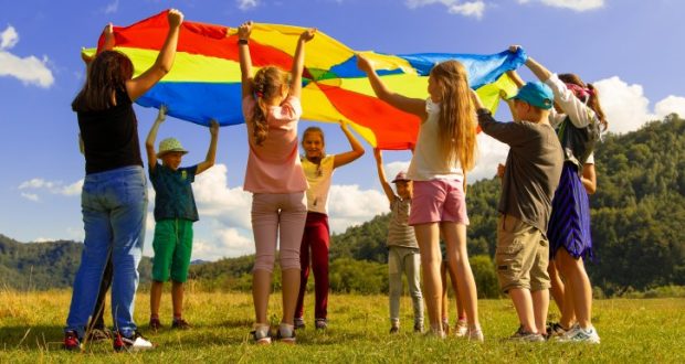 Image of young children outside playing with a parachute canopy.