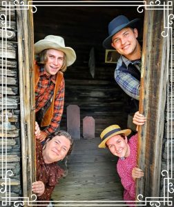 Image of four people in vintage clothing looking out a saloon door.