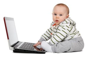 Image of a baby playing on a laptop. 