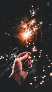 Image of a hand holding a lit sparkler. 