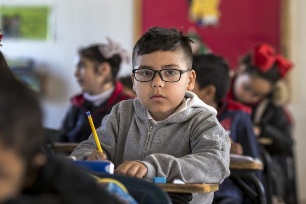 Image of a young boy looking up from his desk in school. 