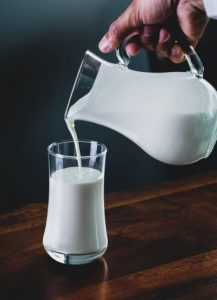Image of a glass of milk being poured from a pitcher. 