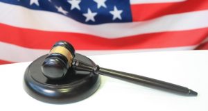 Image of a judge's gavel with an American flag in the background.