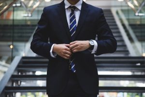 Image of a man buttoning up his suit. 