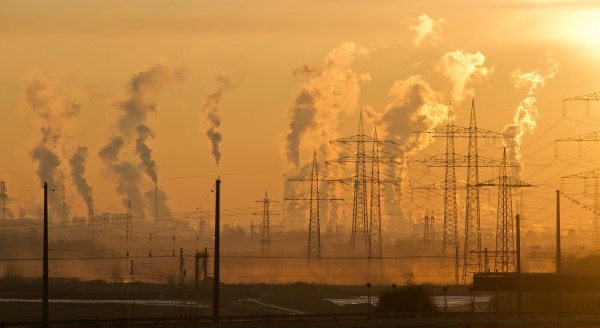Image of a horizon of factories and refineries blowing large amounts of smoke into the air. 
