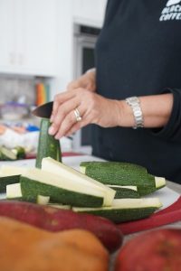 Image of a woman cutting up zucchini.