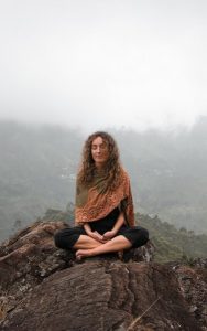 Image of a woman meditating on a mountaintop. 