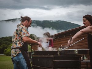 Image of people grilling outdoors with mountains in the background.