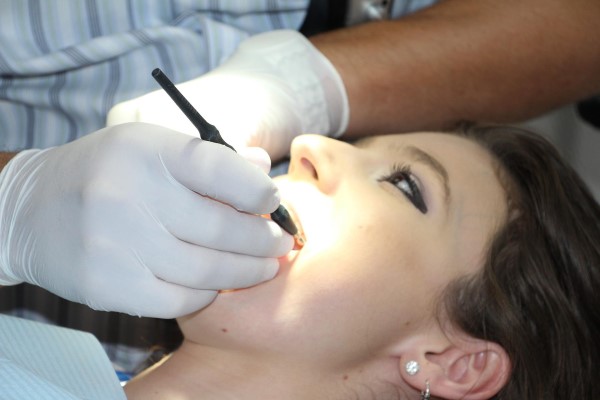 Image of a woman getting her teeth cleaned by a dentist. 