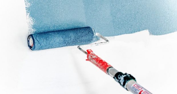 Image of a paint roller painting a white wall blue.
