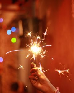 Image of a hand holding up a fire sparkler. 
