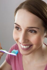 Image of a woman brushing her teeth. 